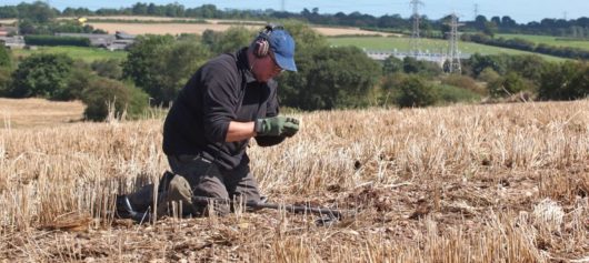 Man metal detecting on his knees and looking at a find